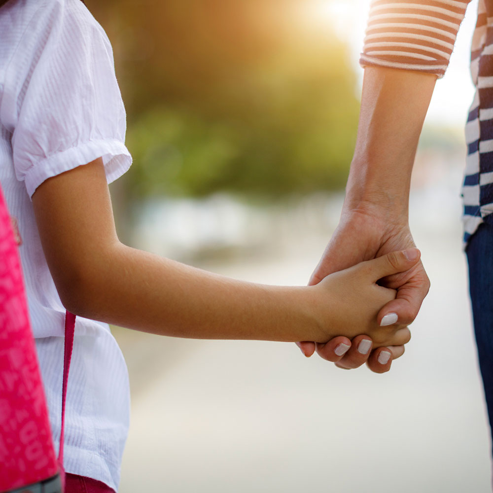 Foster mom holds daughter's hand.