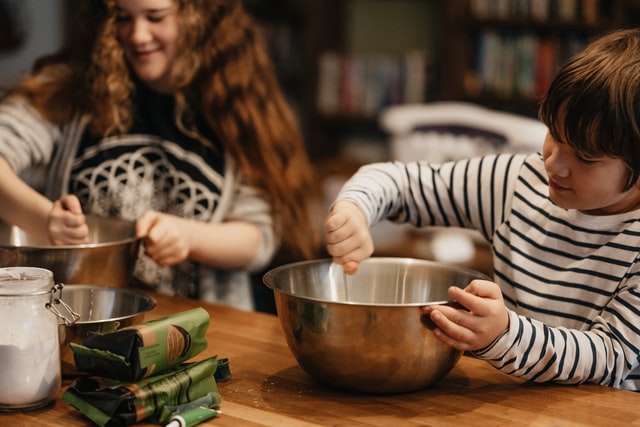 Two kids mixing ingredients in bowls in preparation for a meal