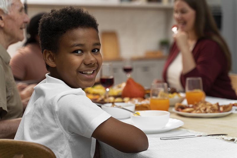 Boy smiling at camera while sitting at a dinner table