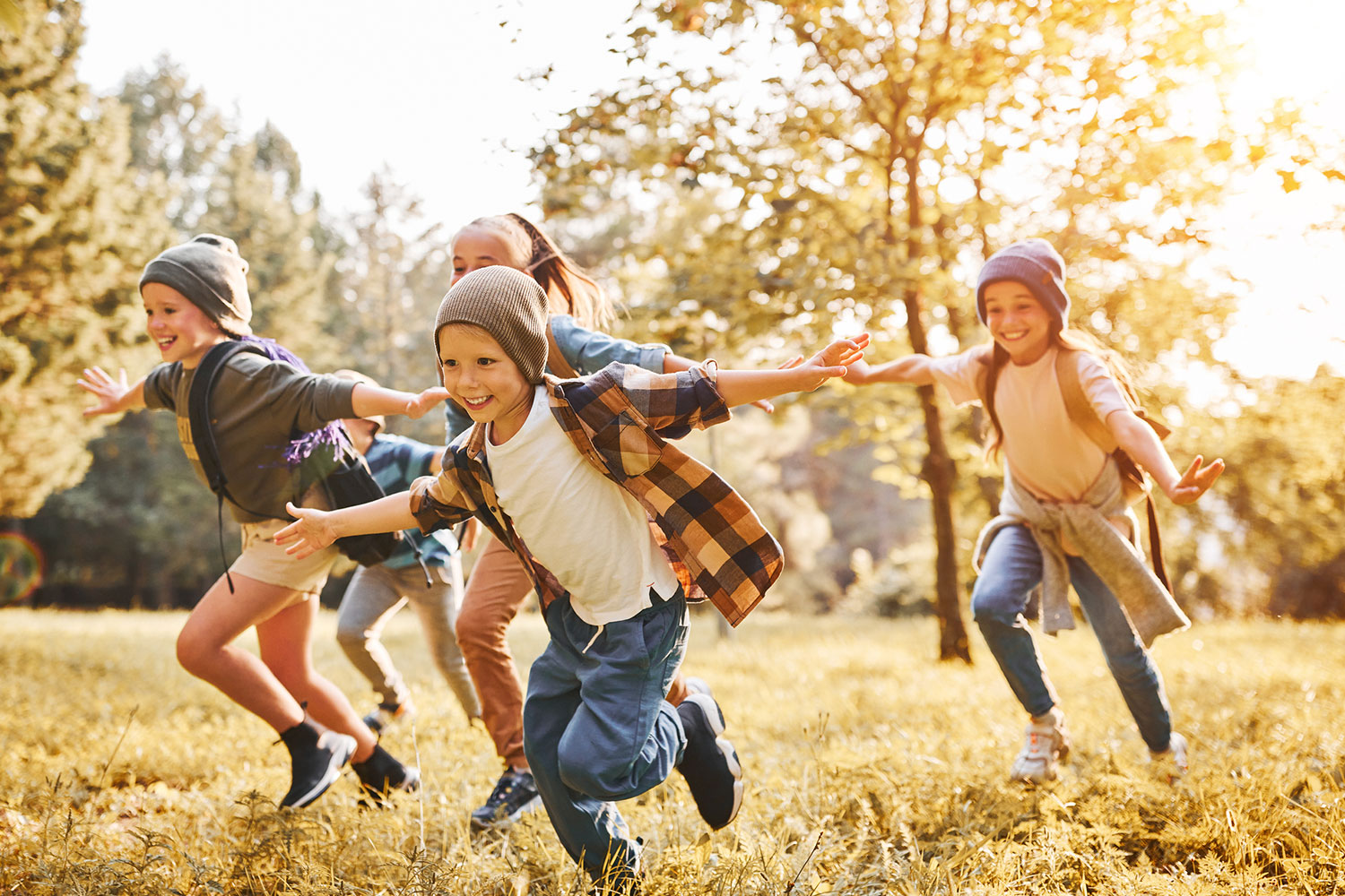 Group of kids play and run through a park